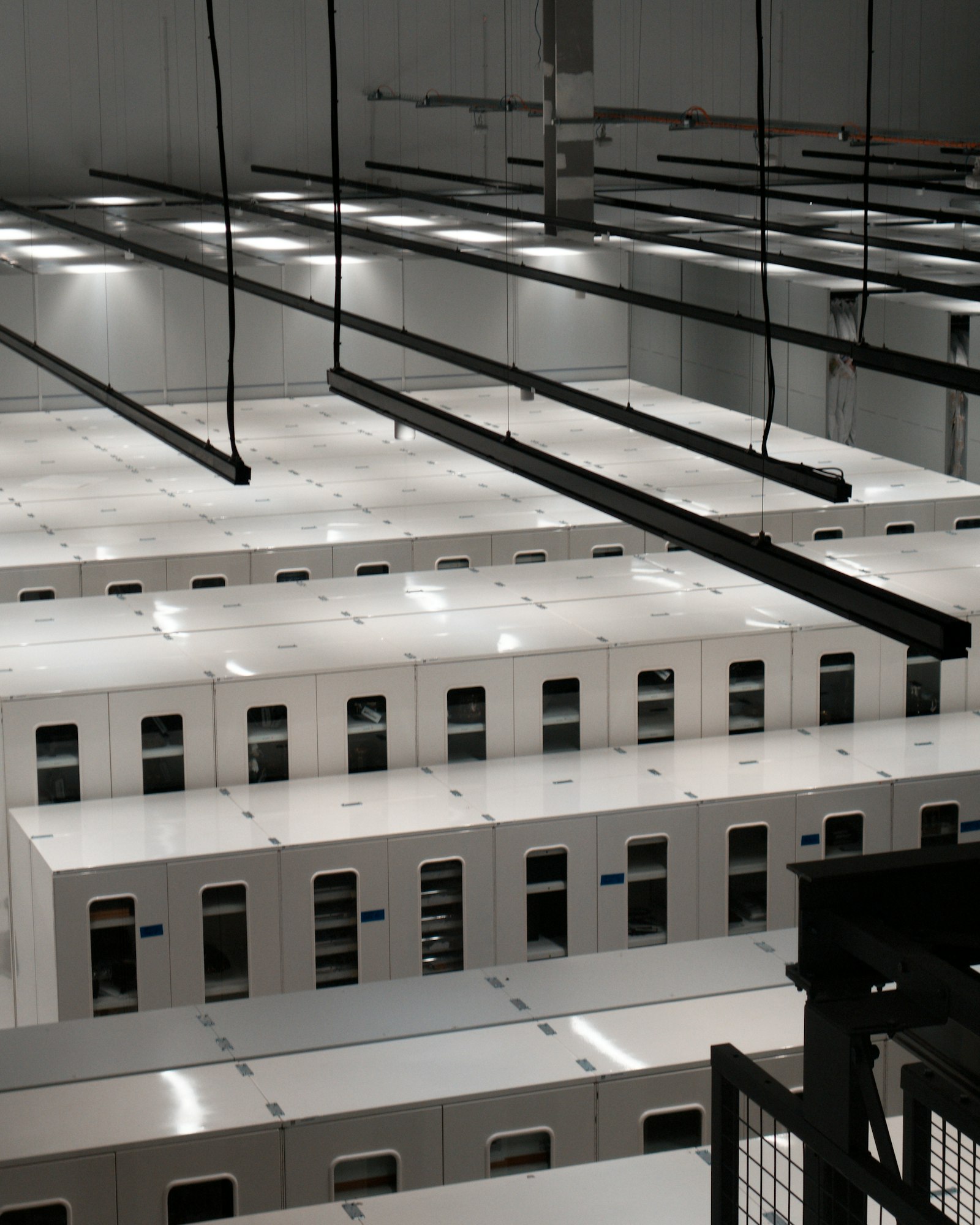 Rows of white server cabinets under overhead lighting in a large data center hall.