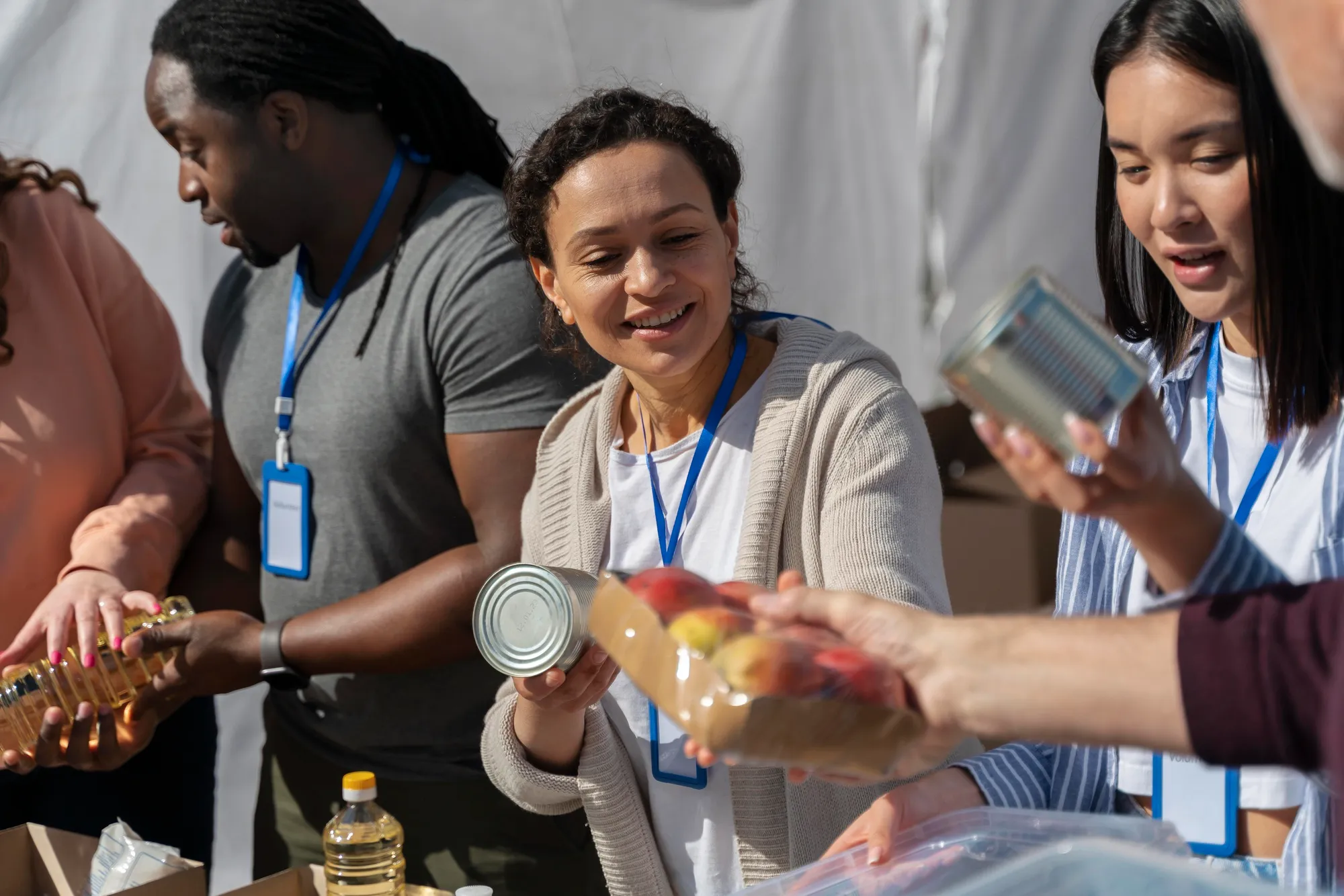 Volunteers sorting and distributing canned food and packaged goods at an aid or charity event.
