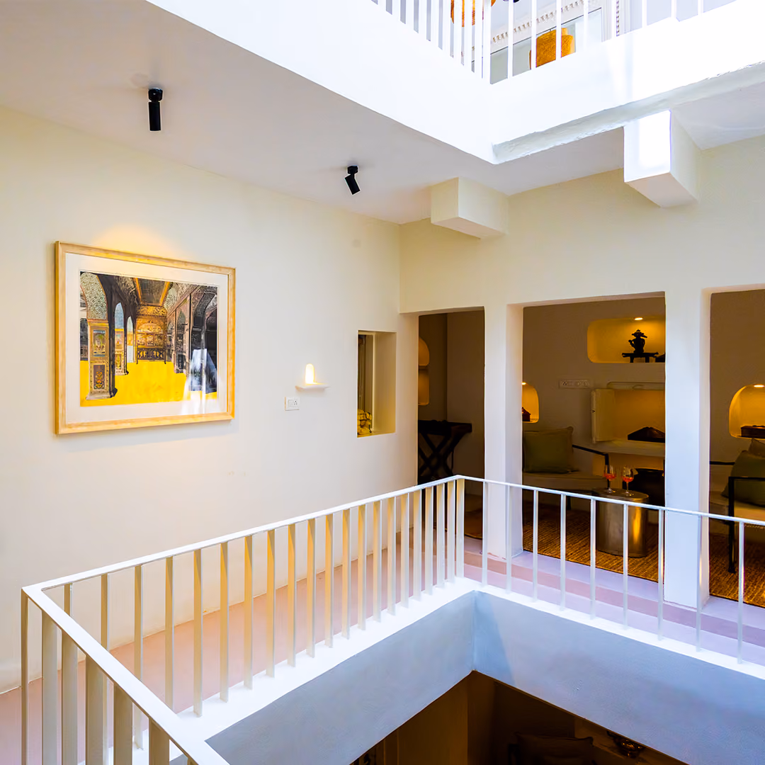 Bright indoor balcony with white railings overlooking a seating area lit with warm lights.