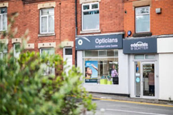 Exterior of an opticians shop on a high street with signage and a brick frontage