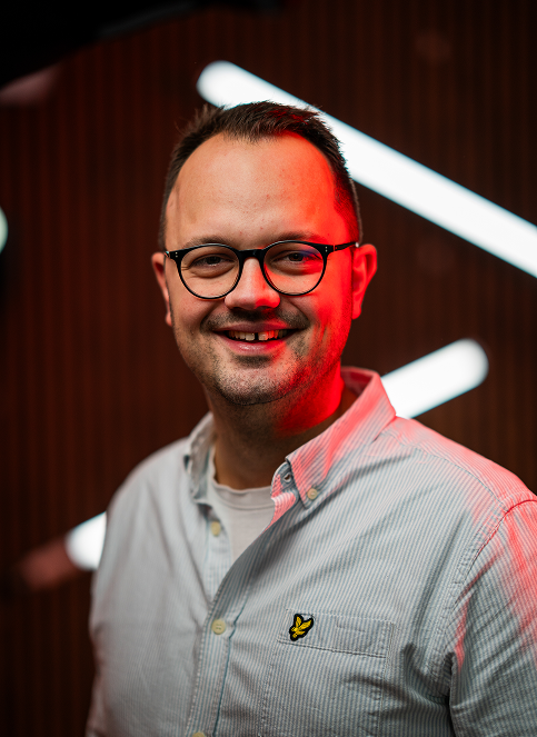 Blauer VW ID. Buzz mit Dachgepäckträger, seitliches Branding "QUIZZ BUZZ", geparkt auf Asphalt.