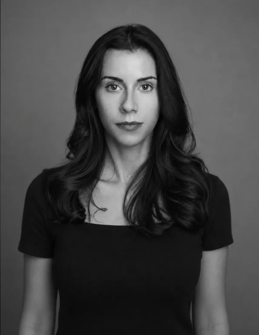 Black and white portrait of a woman with long hair wearing a dark top looking straight ahead.