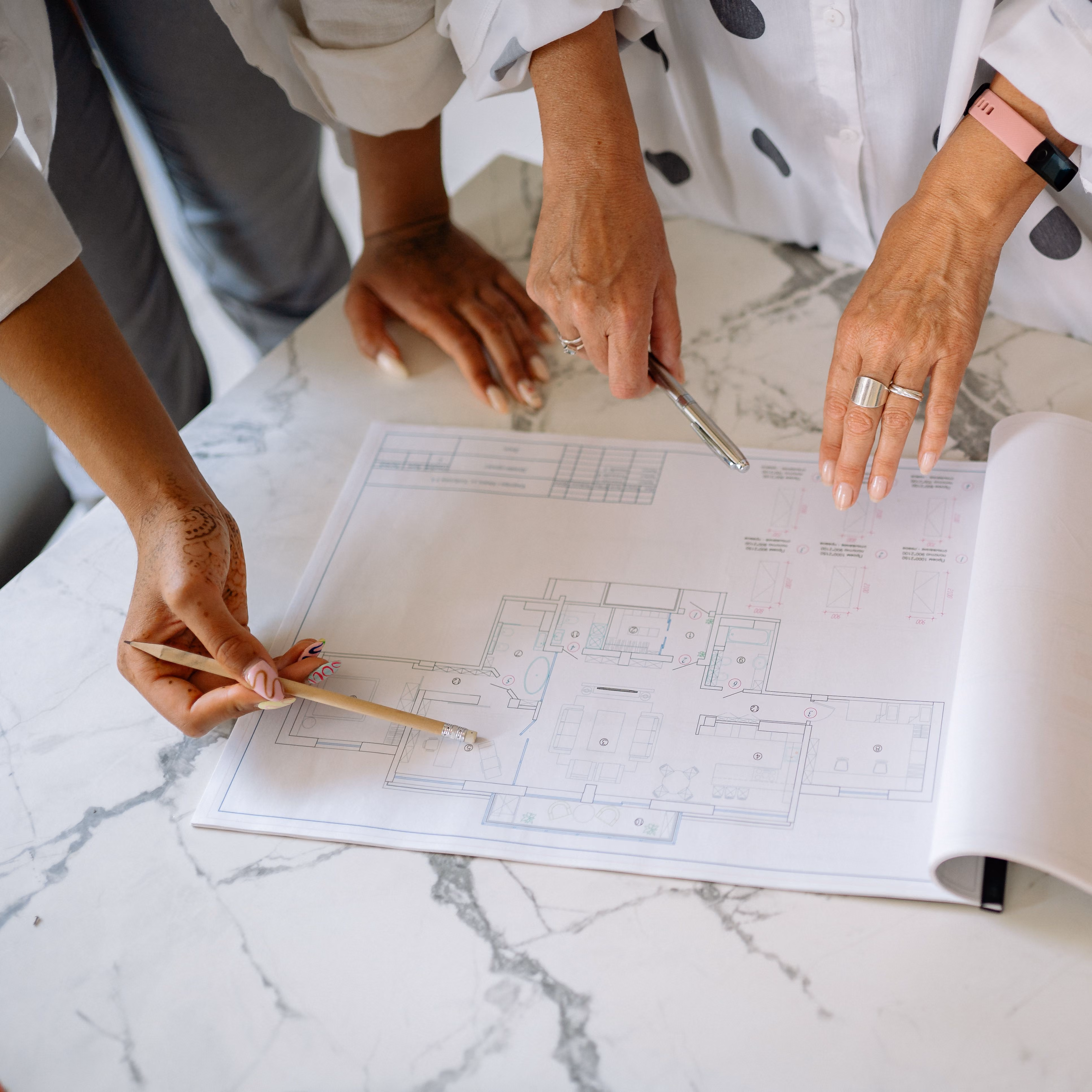 Two people reviewing architectural floor plans with pencils
