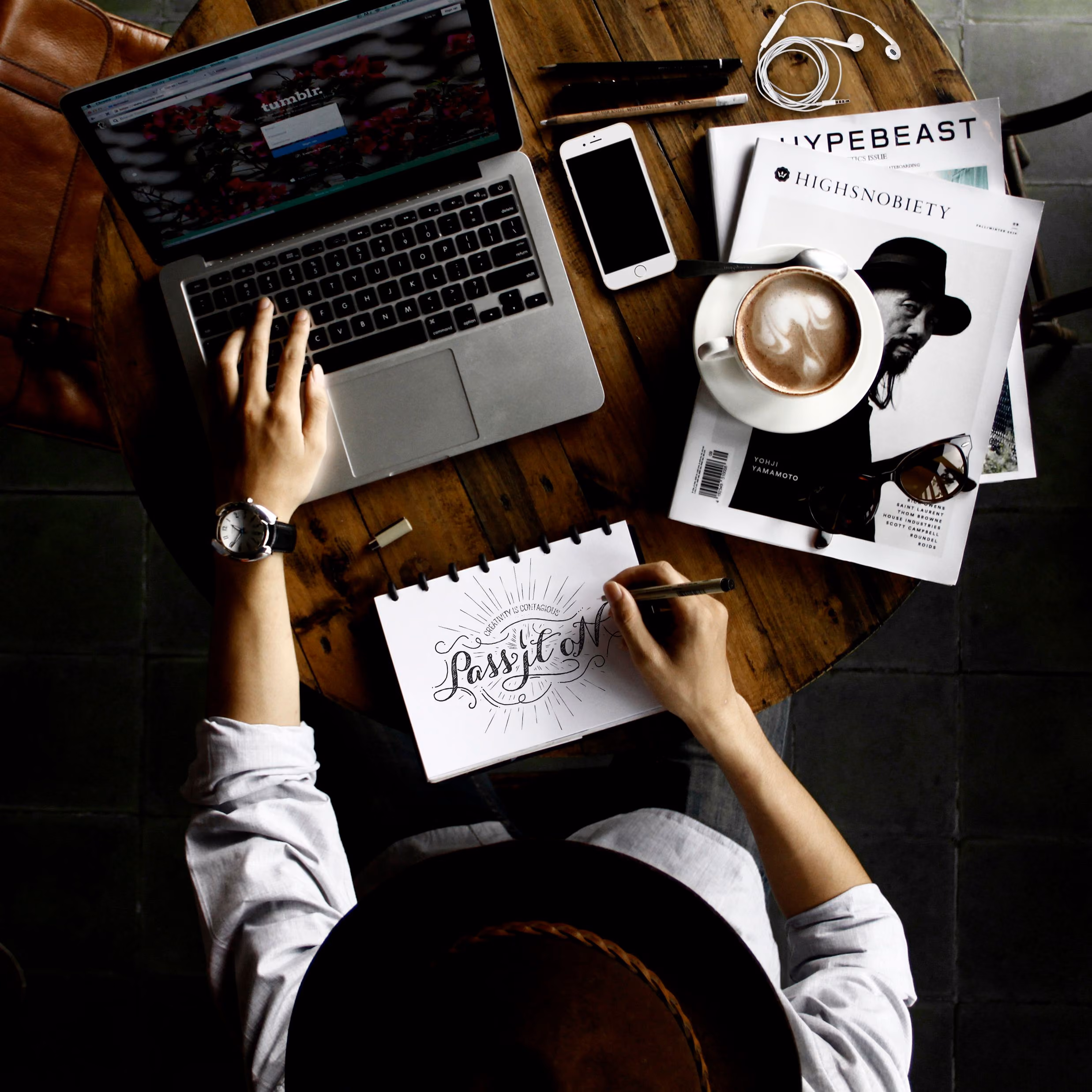 Designer sketching at a desk beside a laptop and coffee