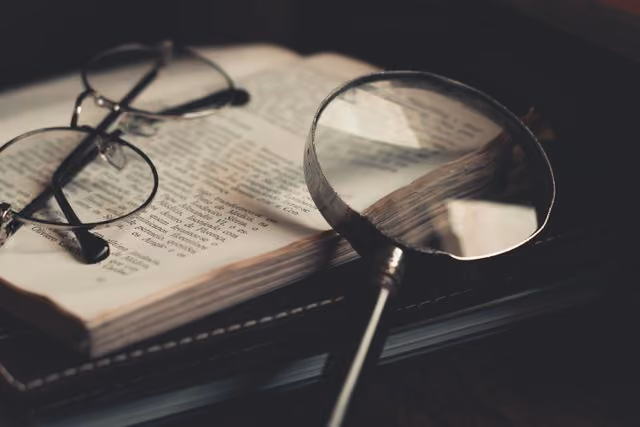 Magnifying glass and glasses resting on an open book