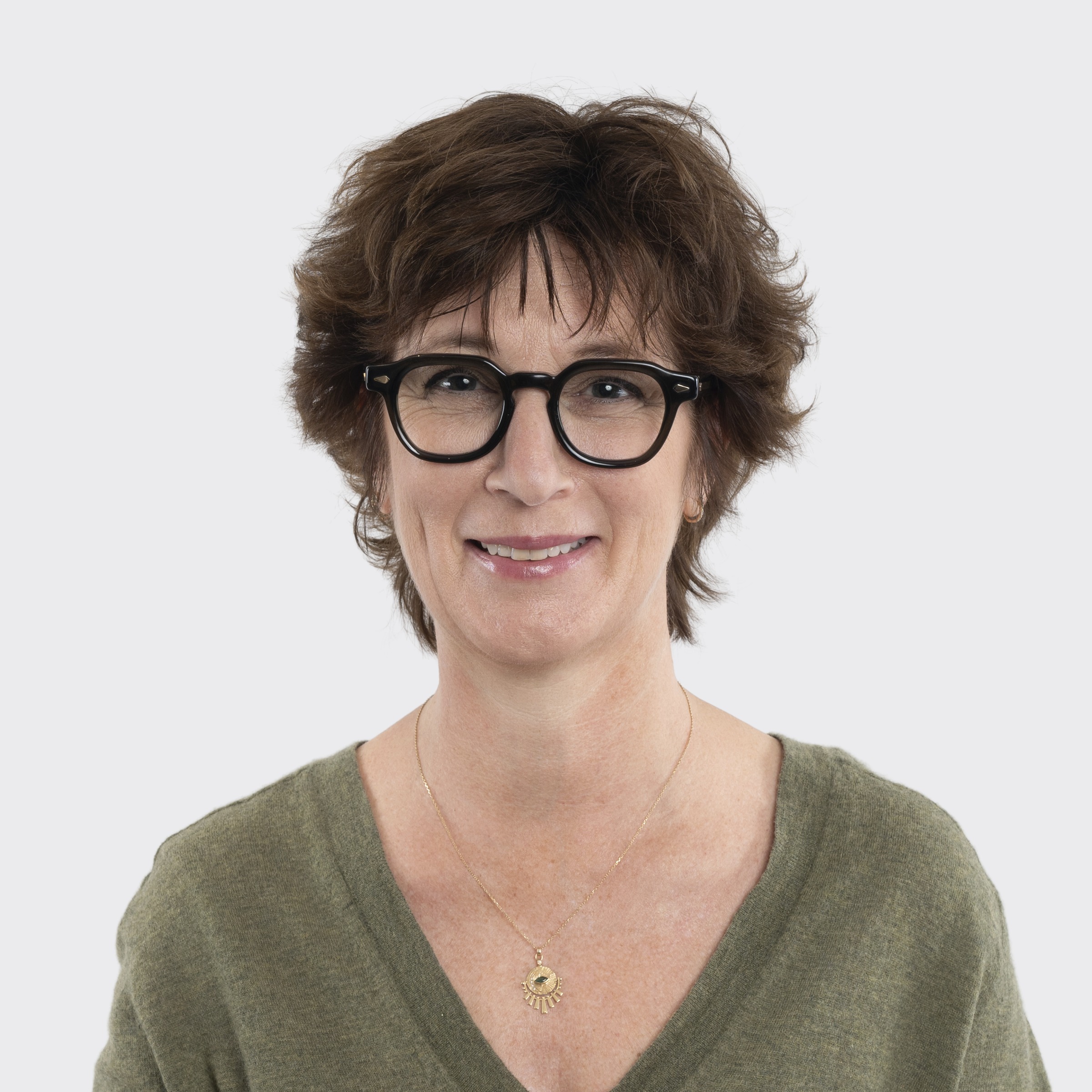 Woman with dark hair smiling, wearing a gray sweater, against a plain light background.