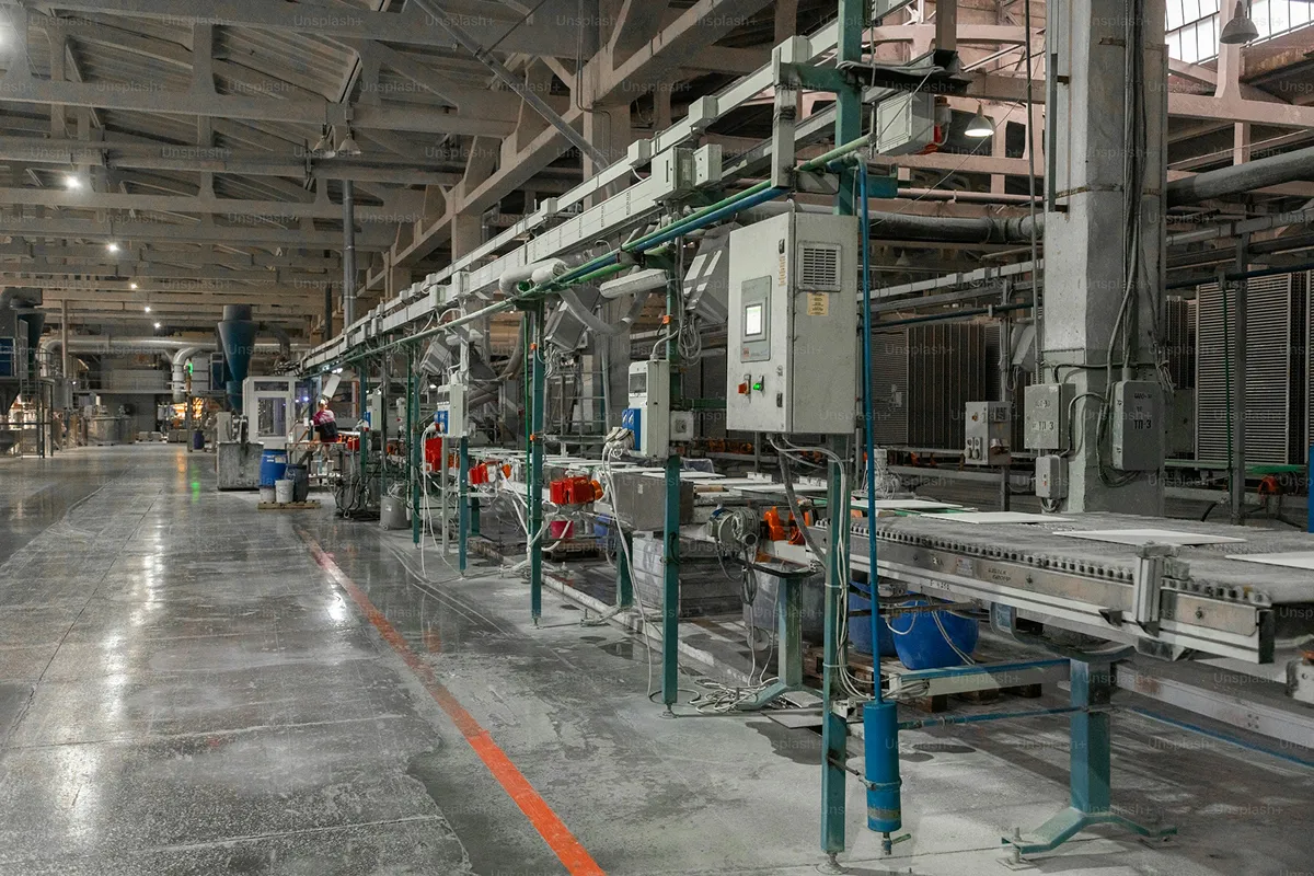 Produktionshalle eines Industriebetriebs mit Förderbändern und technischen Anlagen.