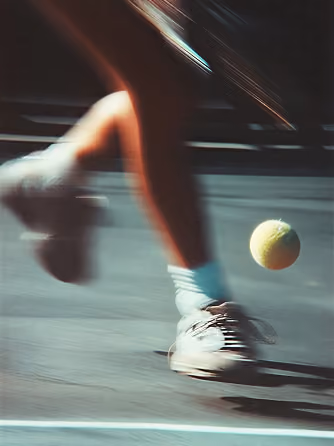 Motion blur shot of a padel player's legs and ball on court