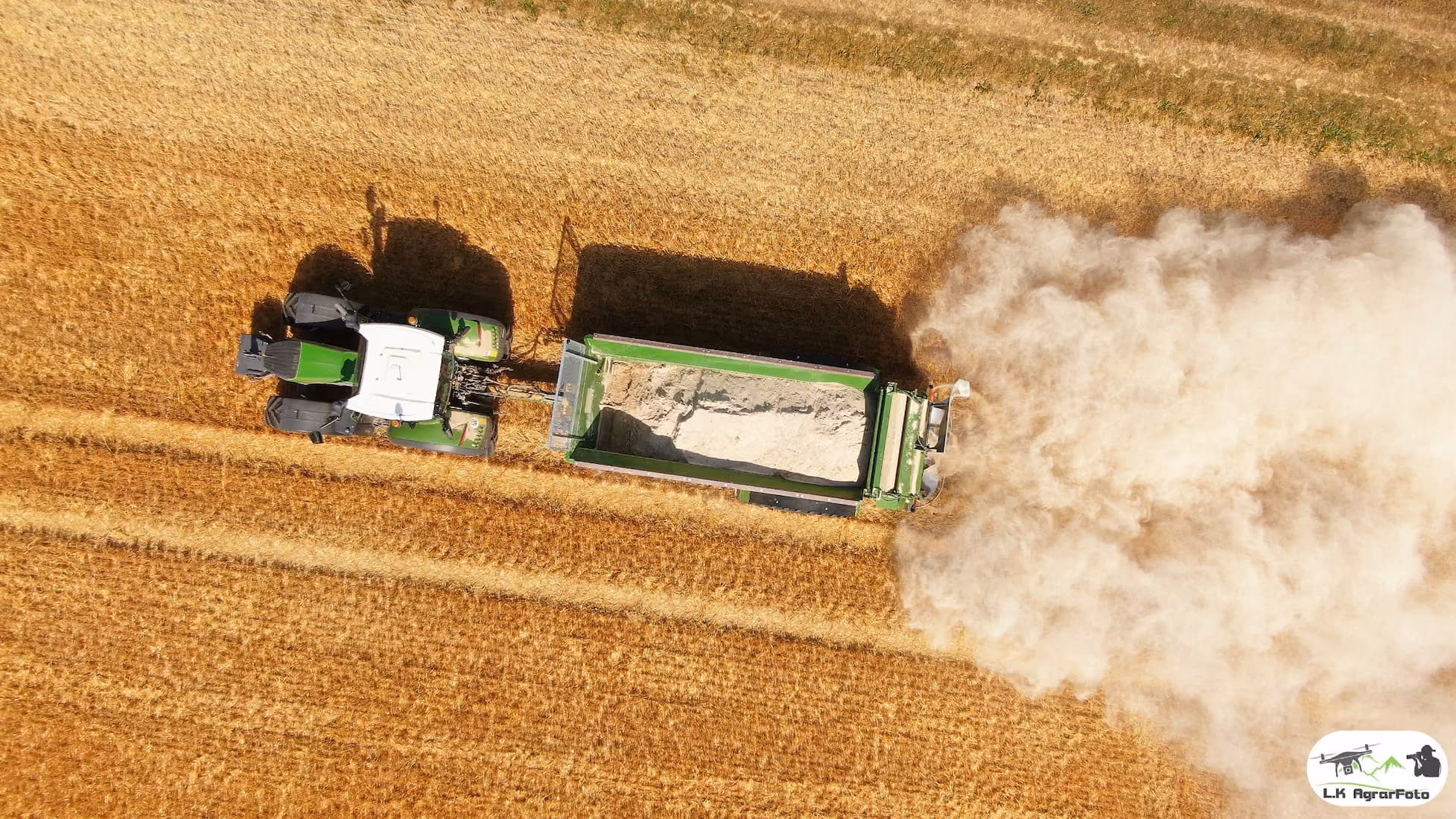 Roter Traktor vom Lohnunternehen Gebr. Schade mit Erdmulde anhänger auf Feld unter blauem Himmel an einem sonnigen Tag in Bad Hersfeld (Hessen)