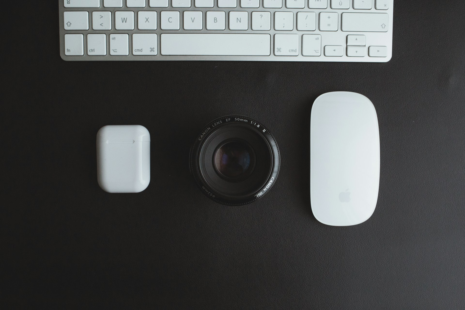 Vue de dessus d'un clavier, d'une lentille d'appareil photo Canon, d'un boîtier d'écouteurs et d'une souris Apple.