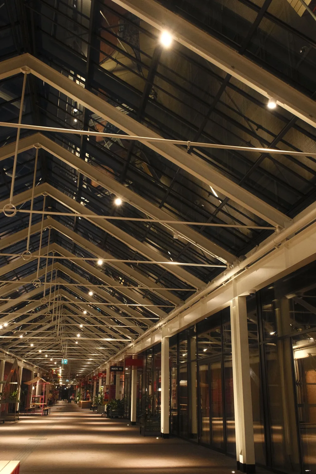 Glass-roofed passage with columns, warm evening light and a view down the hall.