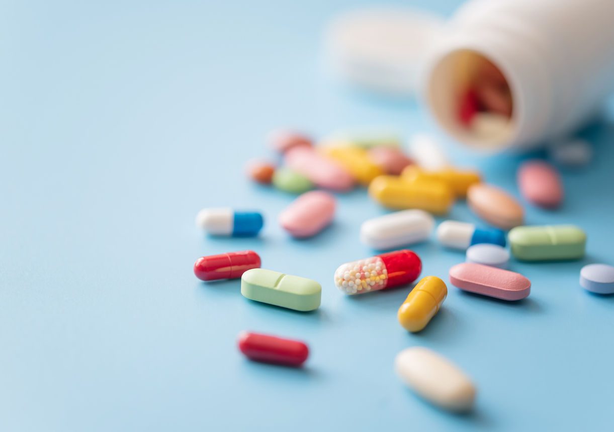 Verschiedene Tabletten und Kapseln liegen neben einem geöffneten Arzneimittelbehälter auf hellblauem Hintergrund: Die Seite bündelt aktuelle Zahlen zu Generika. Copyright: © igoriss/iStock