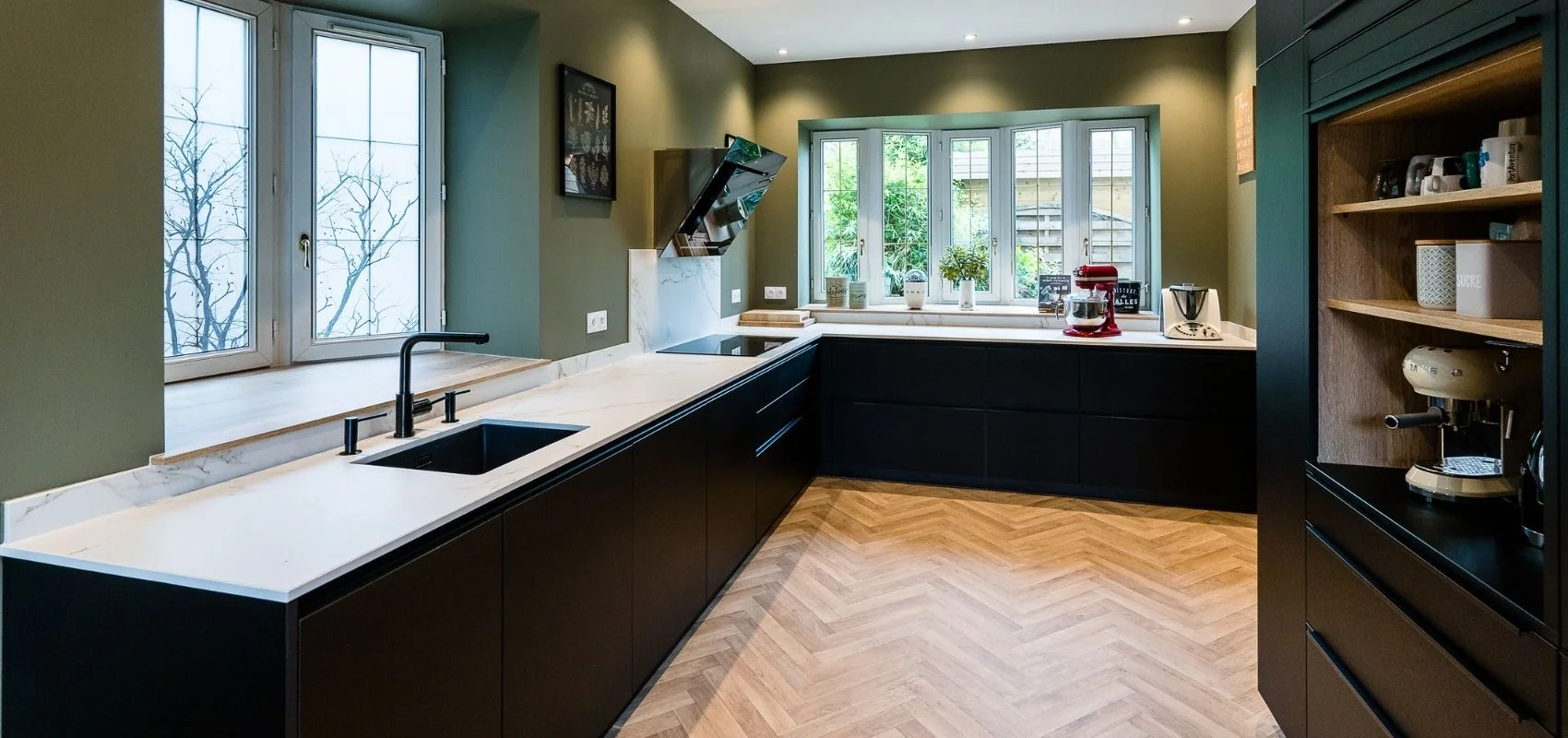 Cuisine sur mesure noire avec murs vert olive et parquet en chevrons réalisée par So!Cozi