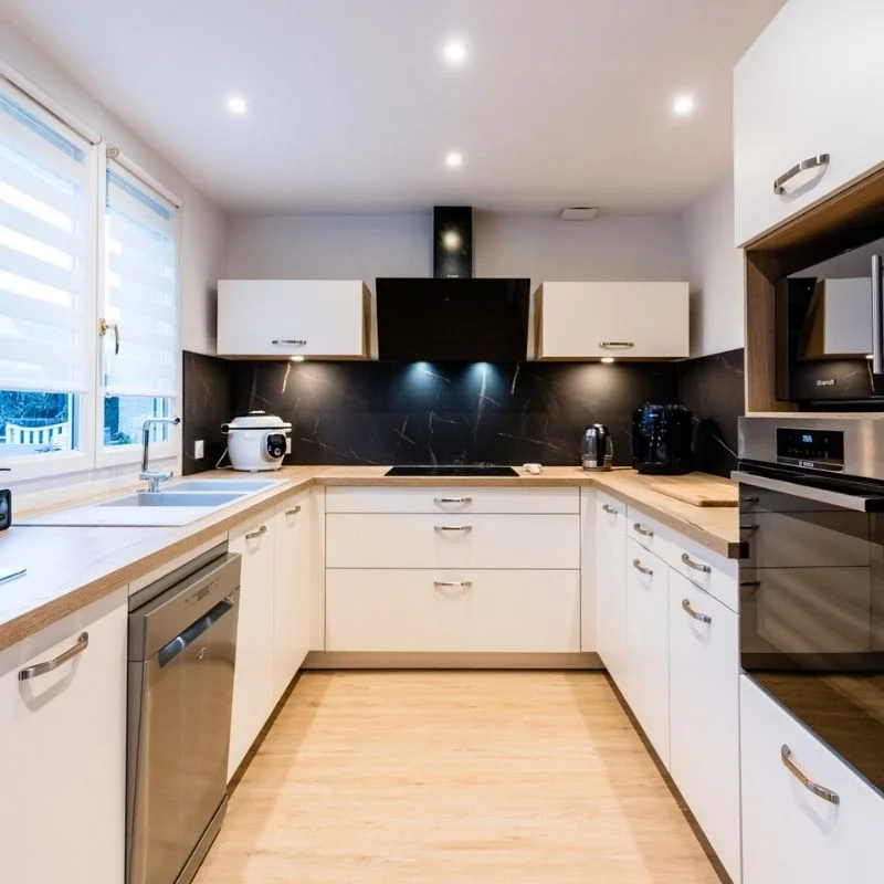 Cuisine en U blanche avec plan de travail bois, crédence en marbre noir et hotte design, réalisation So!Cozi