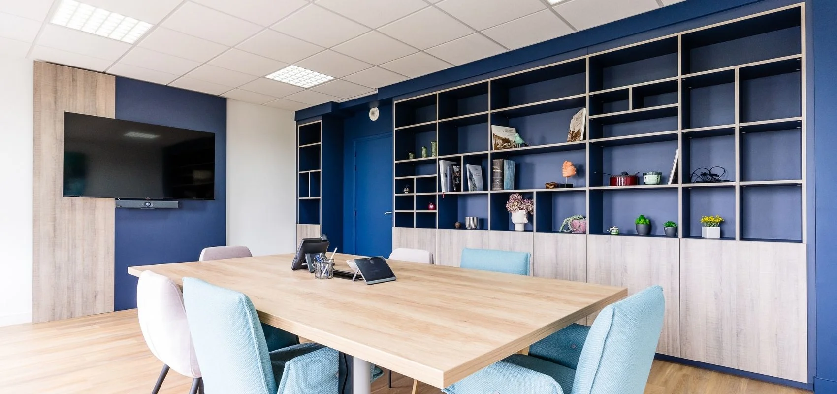 Bibliothèque murale bleu marine et bois avec écran TV intégré, aménagement de salle de réunion So!cozi