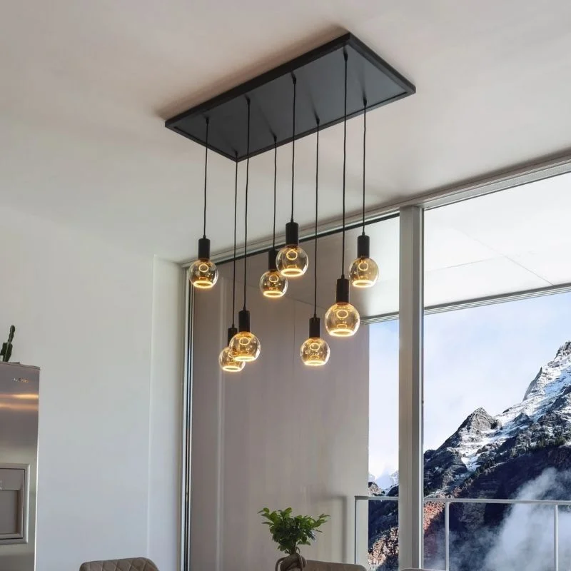 Luminaire de plafond moderne doté de huit ampoules sphériques suspendues, dans une pièce avec des fenêtres offrant une vue sur les montagnes.