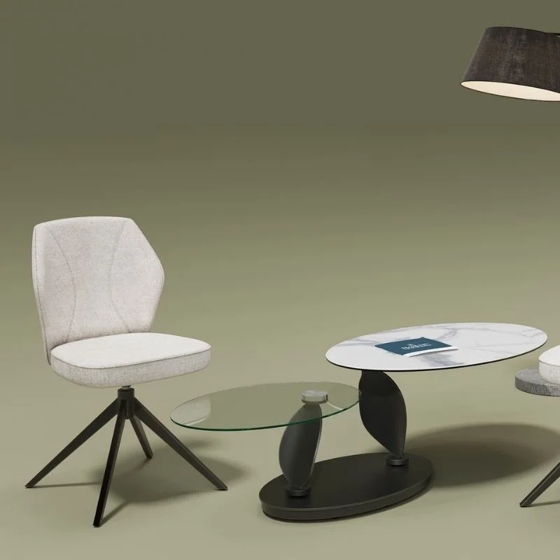 Chaise Vienna Akante beige rembourrée avec pieds en métal noir, placée à côté de deux tables basses aux plateaux en verre et en marbre.