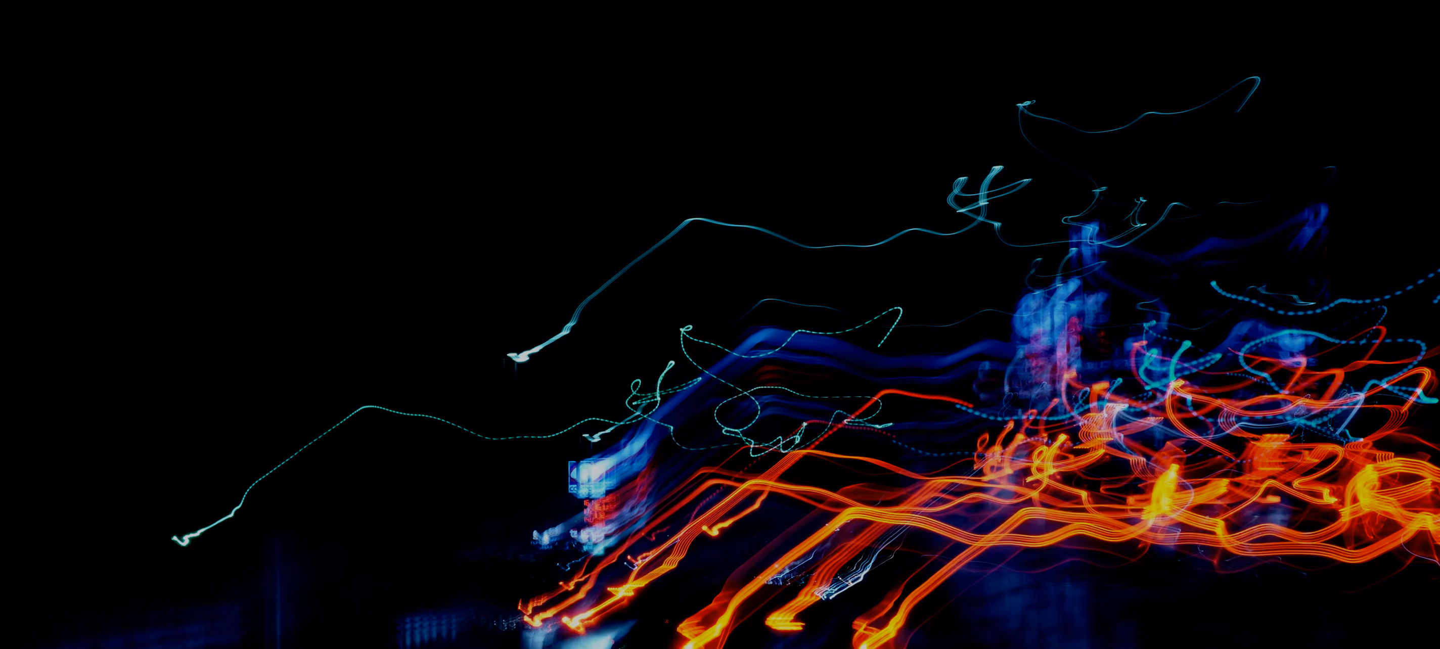 Abstract light trails in blue, orange, and red on a black background creating dynamic motion patterns.