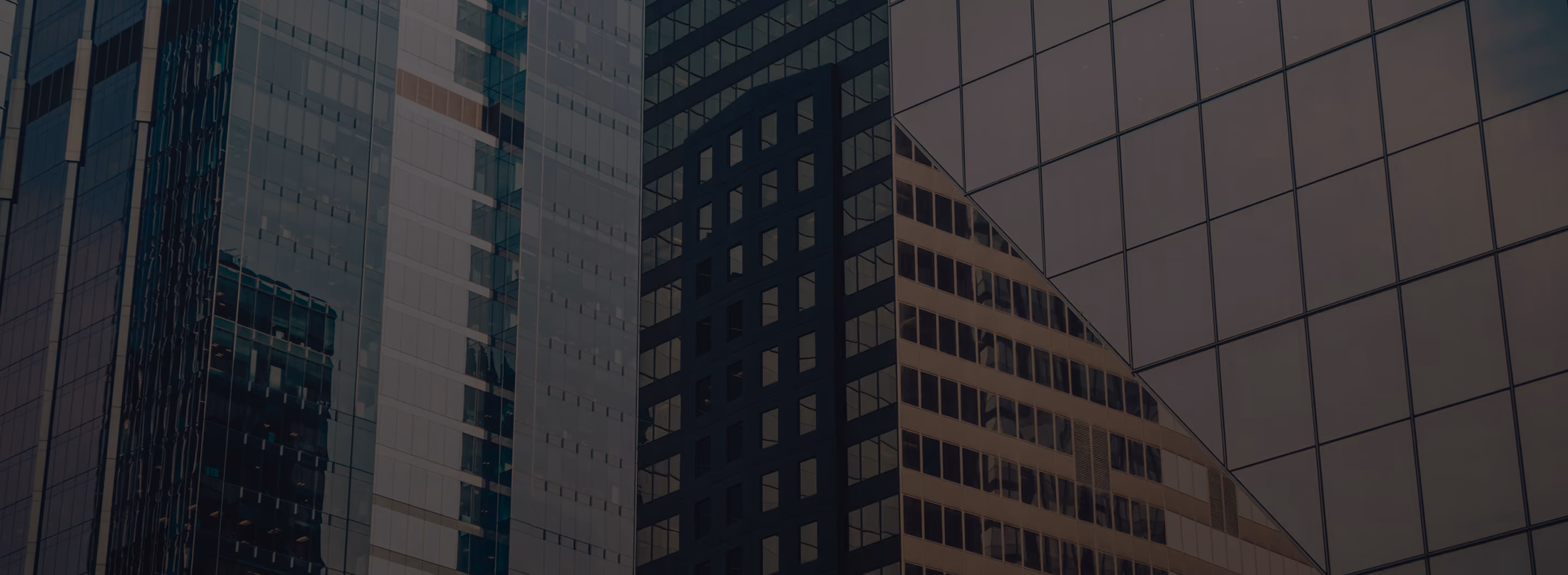 Close-up of modern office buildings with glass windows reflecting neighboring structures.
