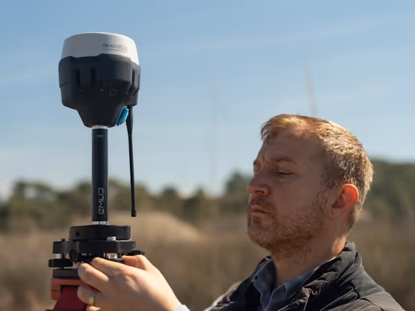 Surveyor mounting a GNSS receiver on a survey tripod