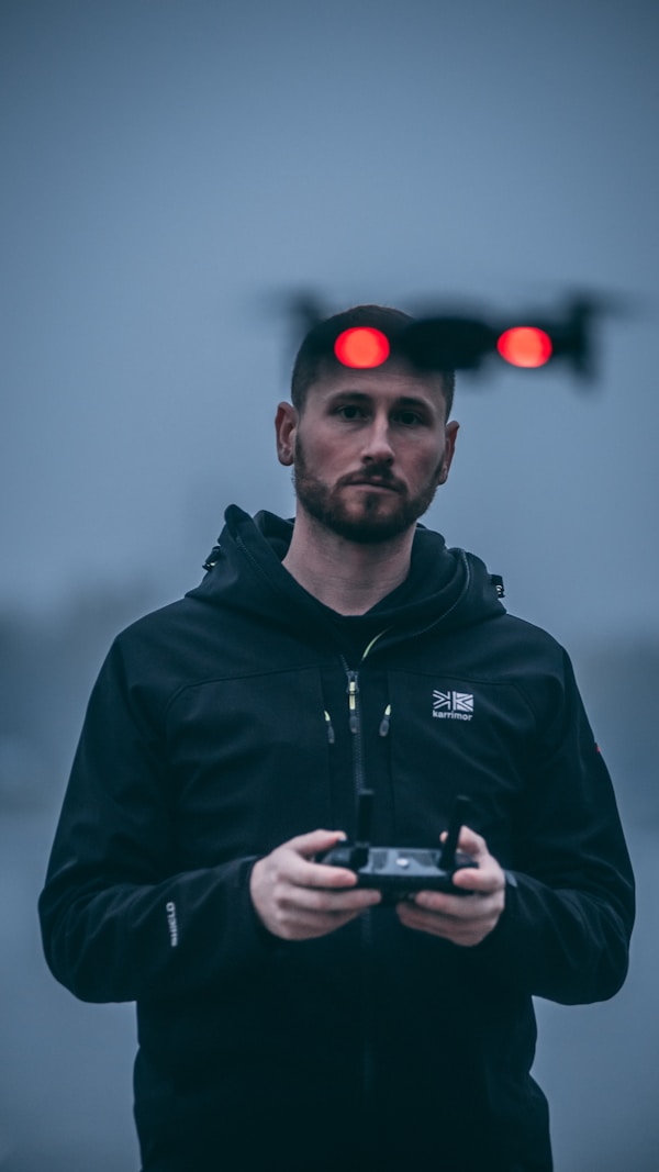 man in black zip up jacket holding black smartphone
