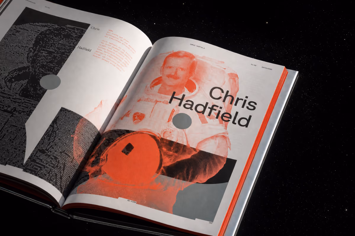 Aufgeschlagenes Buch zeigt Bild von Chris Hadfield im Raumanzug vor schwarzem Sternenhintergrund.