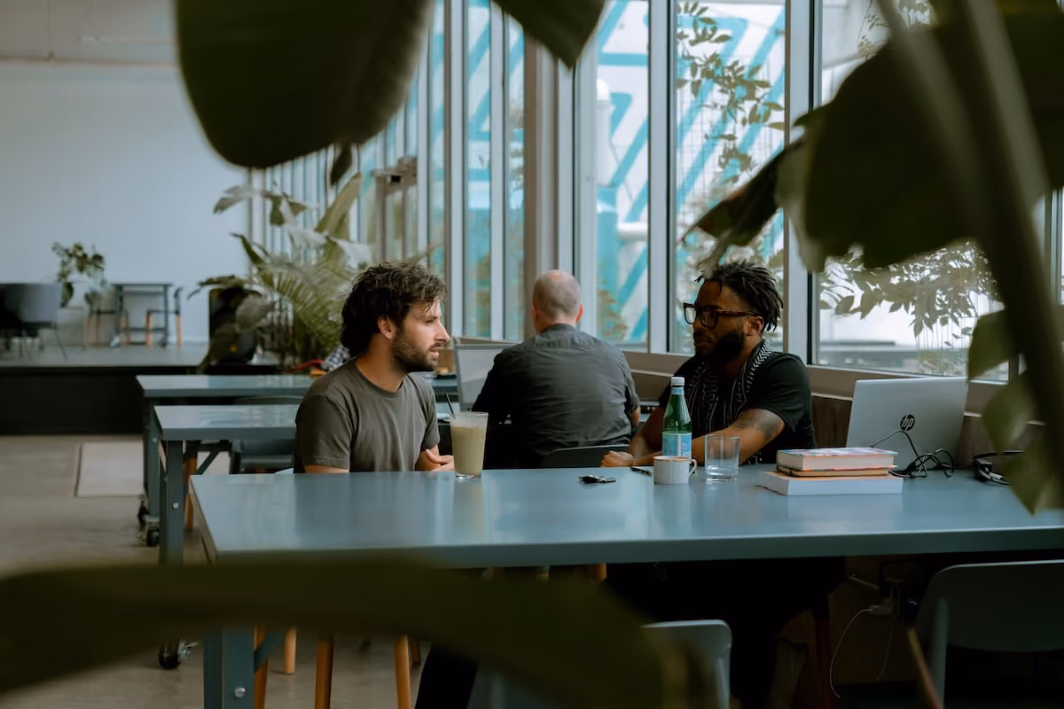 Three colleagues talking at a long canteen table