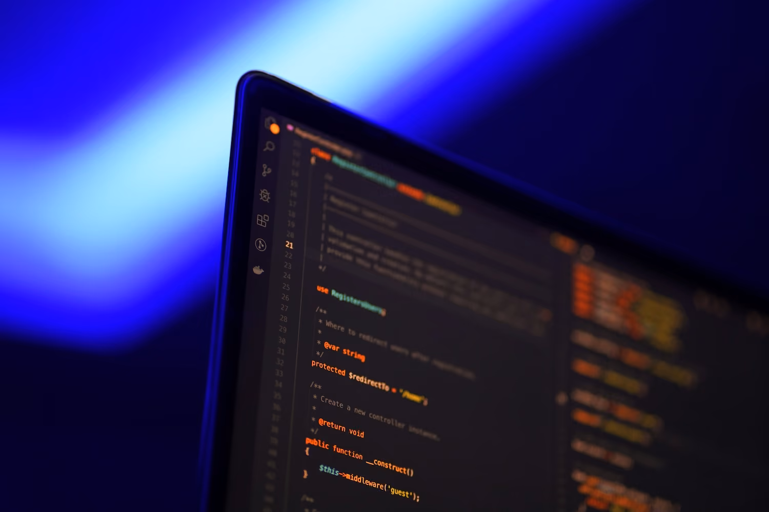Close-up of a laptop screen displaying colorful lines of code in a dark-themed editor with a blurred blue light background.