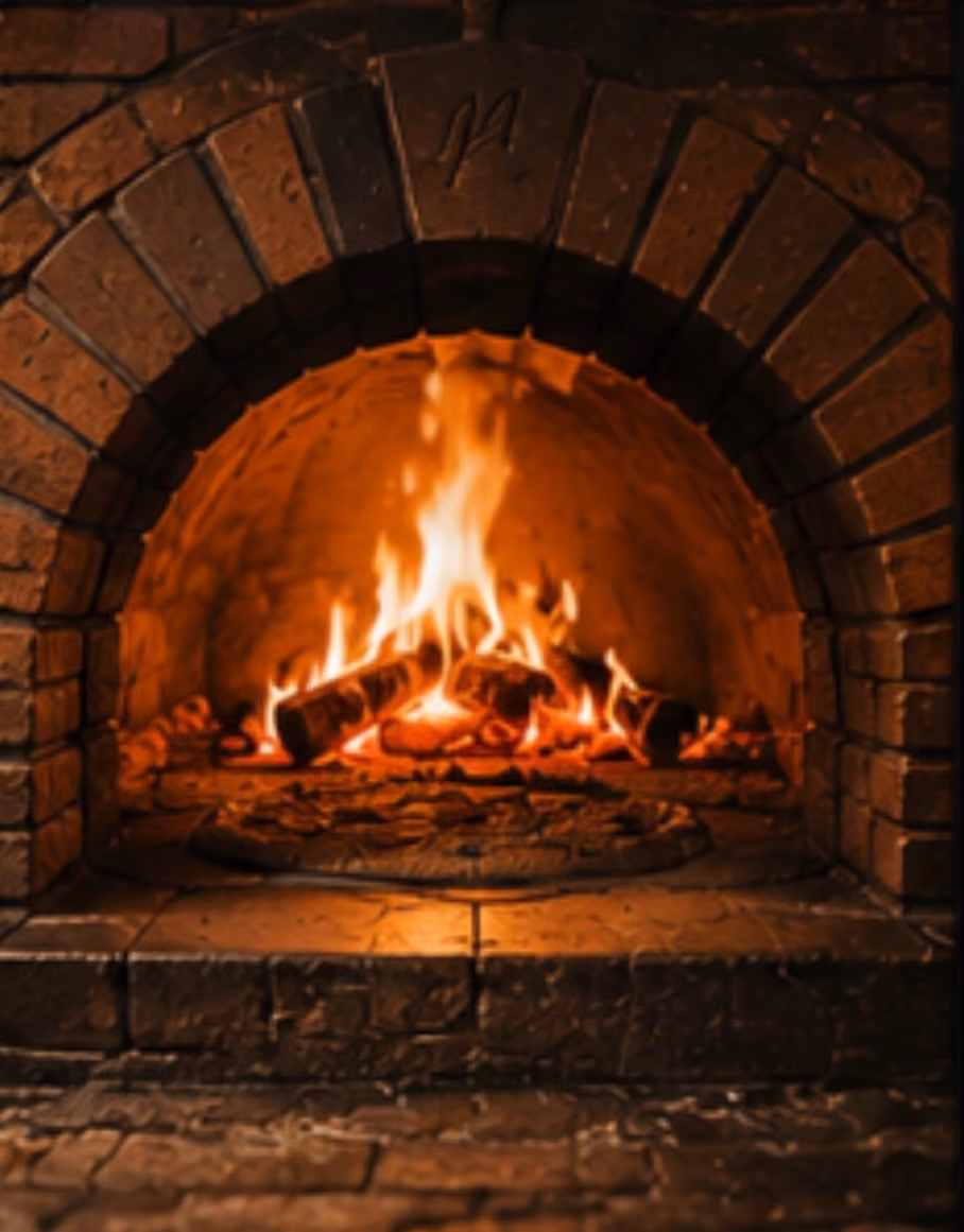 Lit firewood burning inside a curved brick fireplace with warm orange flames.