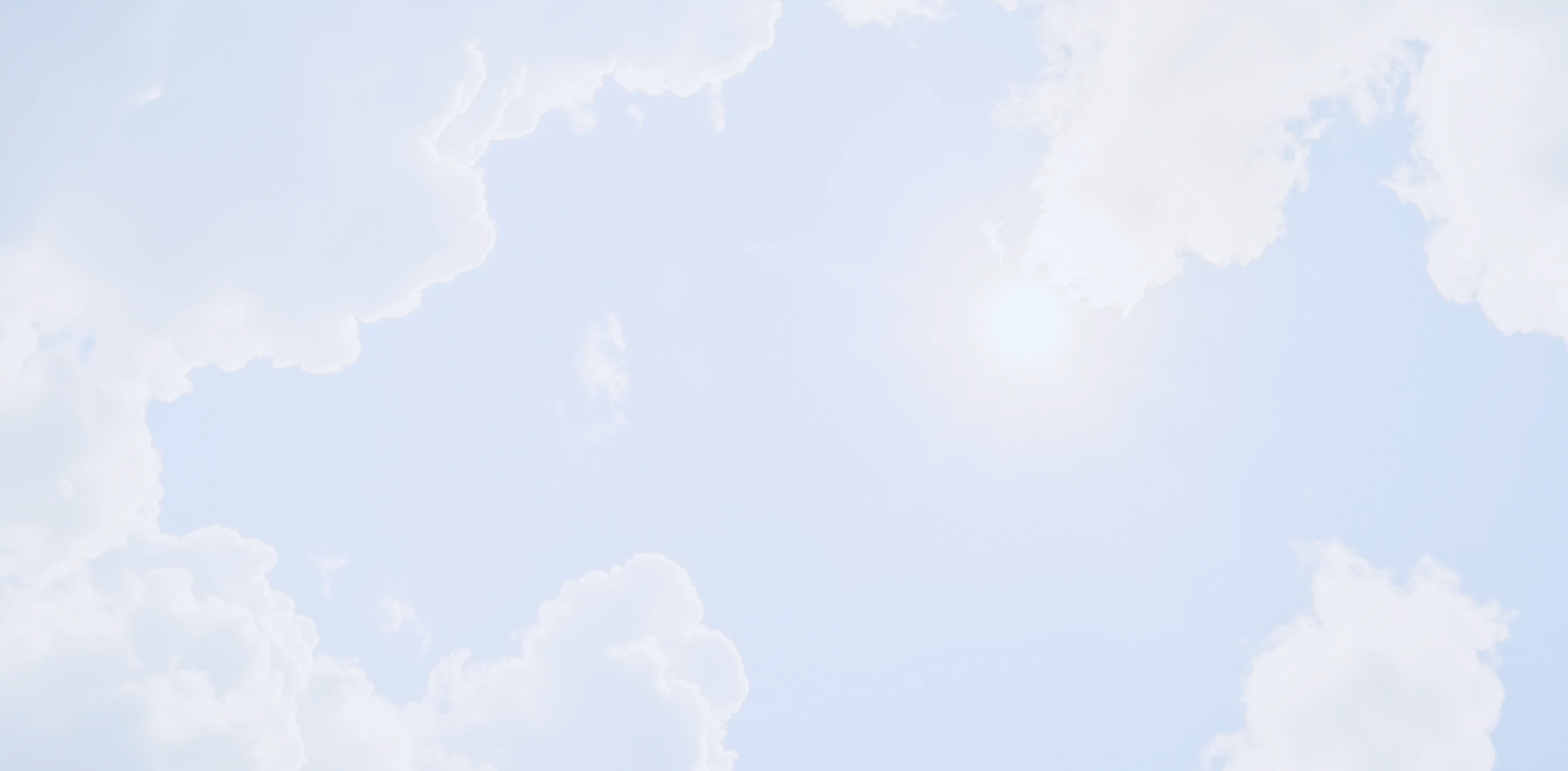Blue sky with bright sun and scattered white fluffy clouds around the edges.