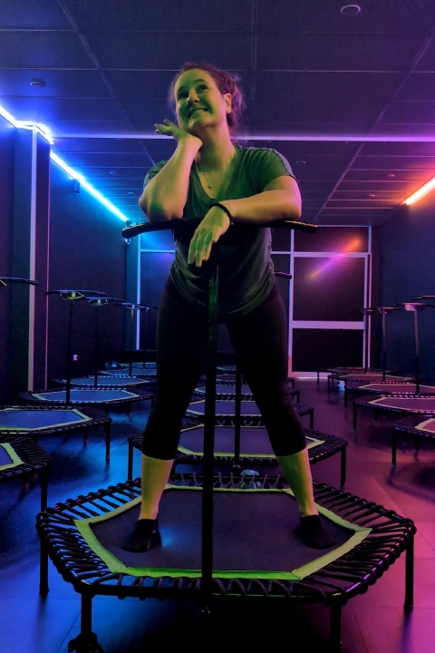 Woman standing on a rebounder trampoline inside Bounc'd NQ in Earlville, QLD, with colorful studio lighting ready for class.