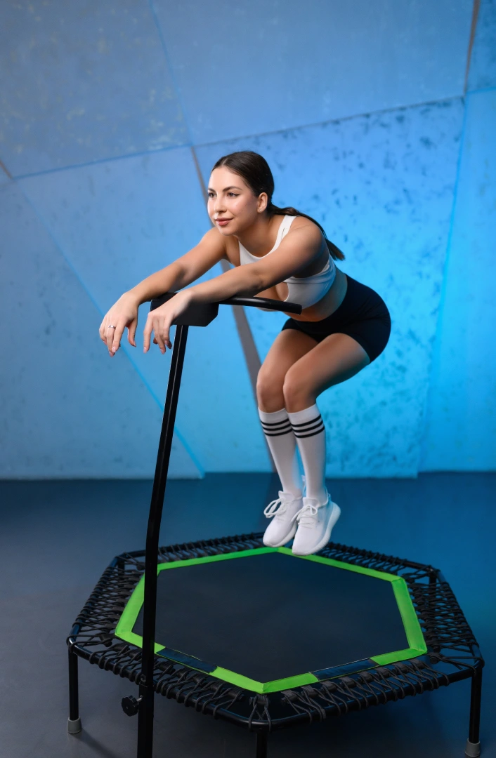 Woman performing a low-impact rebounder workout at Bounc'd NQ in Earlville, QLD, using a stability bar for balance and control.