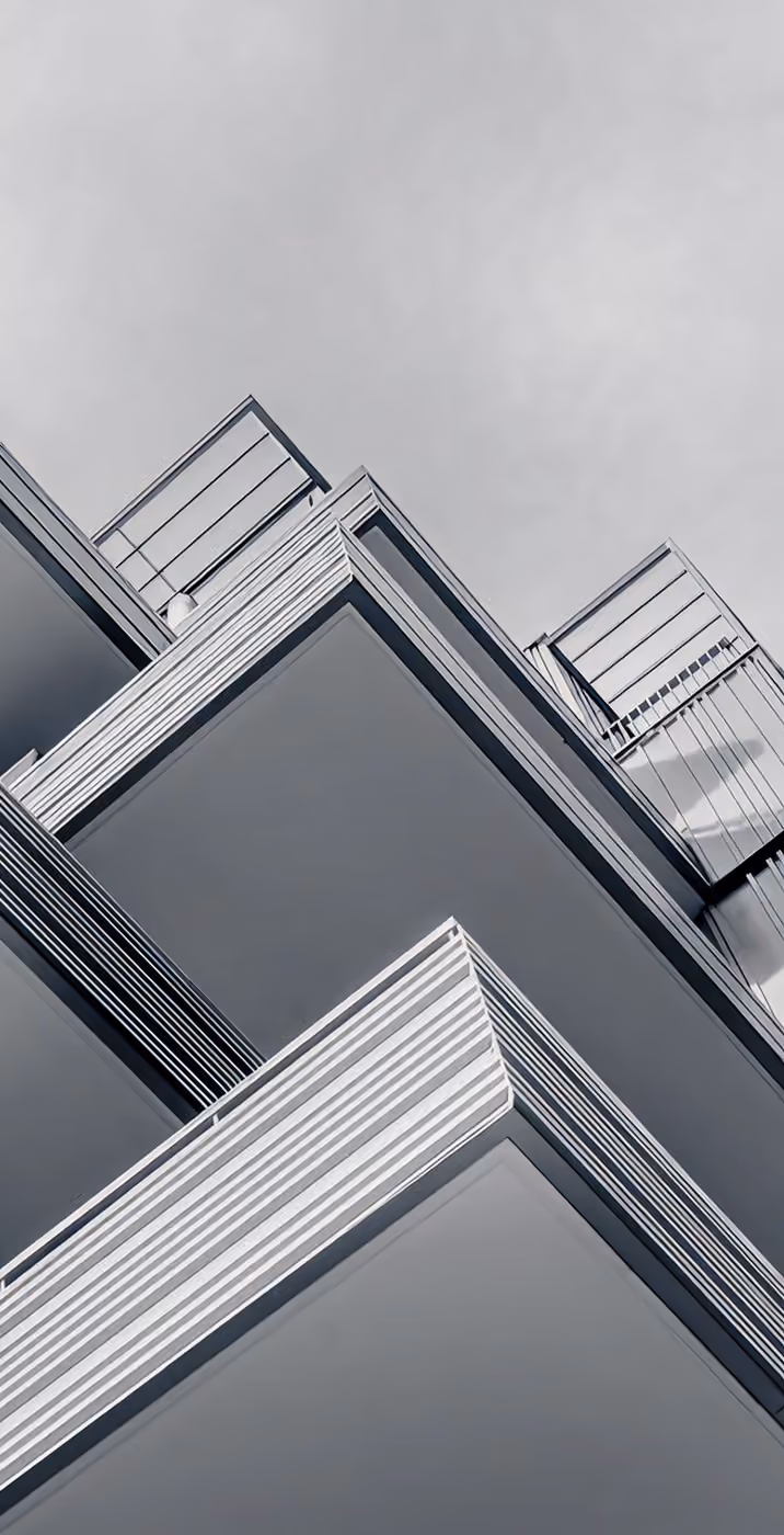 Angular view from below of a modern building with multiple stacked balconies and railings.