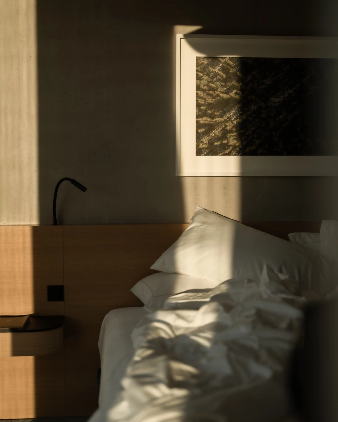 Chambre ensoleillée avec draps blancs et tête de lit en bois dans un condo de Rive Lac Tremblant