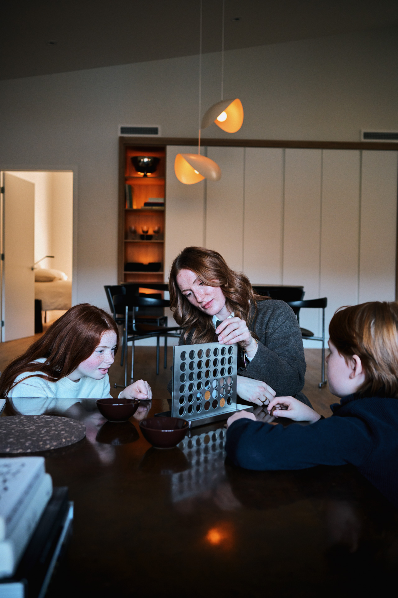 Mère et enfants jouant à un jeu de société à la table d'un condo de Rive Lac Tremblant