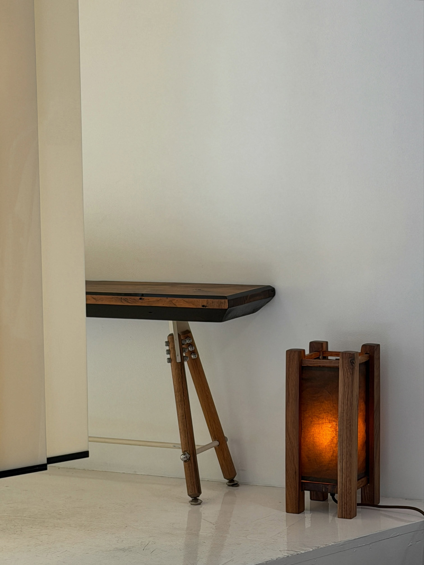 Lampe lanterne en noyer à abat-jour de papier ambré à côté d'une console en bois sur pieds trépied