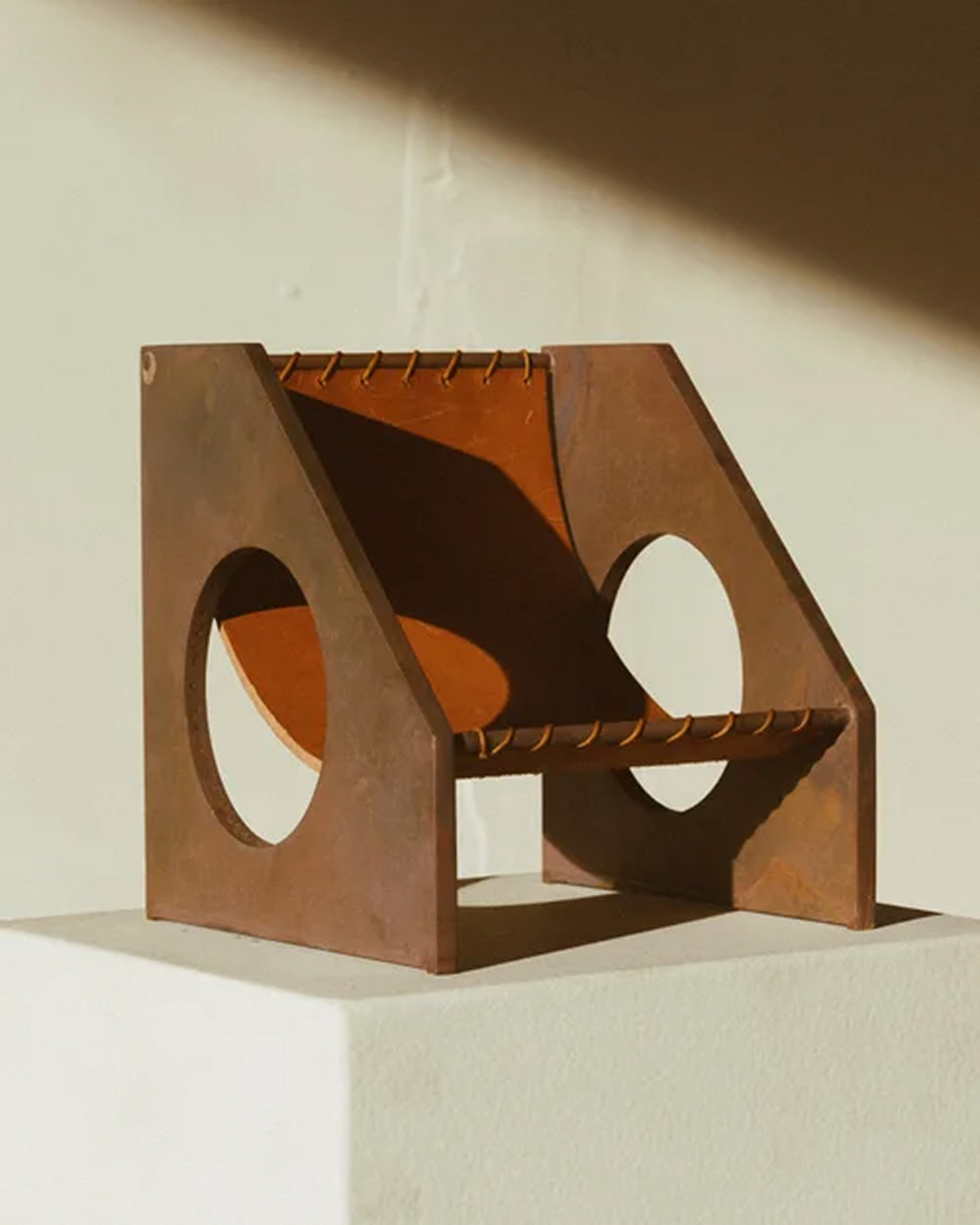 Fauteuil sculptural en acier rouillé et cuir aux découpes circulaires sur un socle