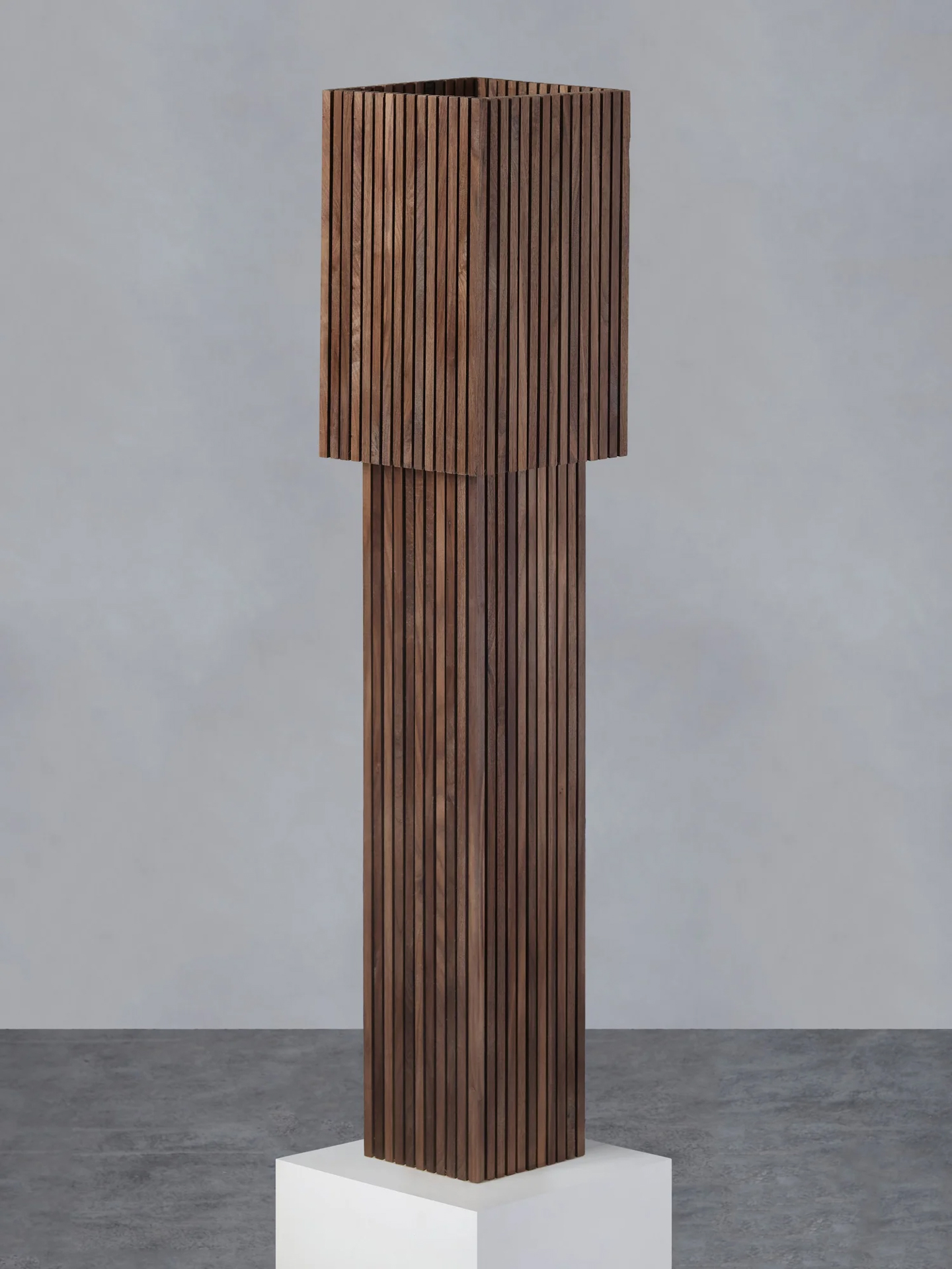 Tall slatted walnut floor lamp by Stamatios on a white plinth