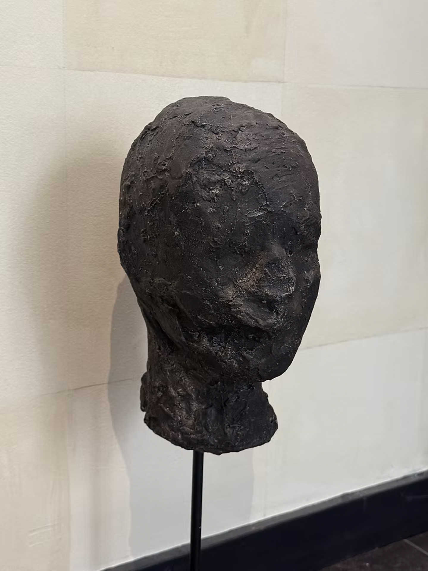 Textured dark bronze head sculpture by Oda and King on a slender stand
