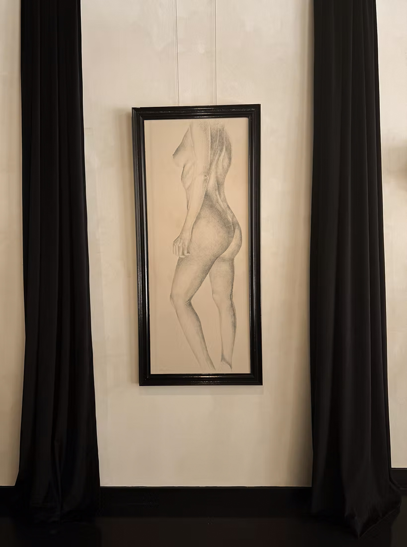 Framed graphite figure drawing by Oda and King hung between black velvet curtains