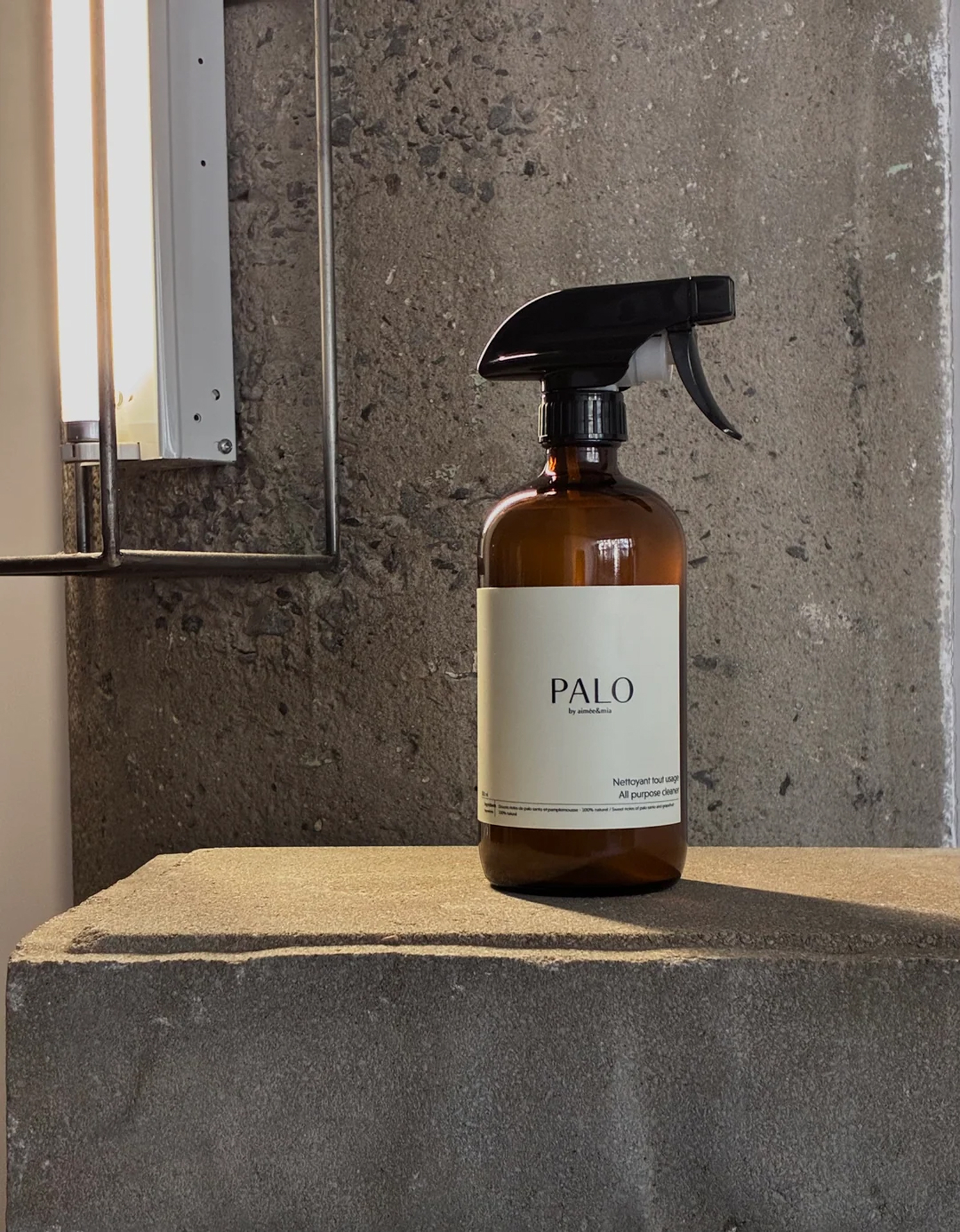 Palo all-purpose cleaner in an amber glass spray bottle on a concrete ledge