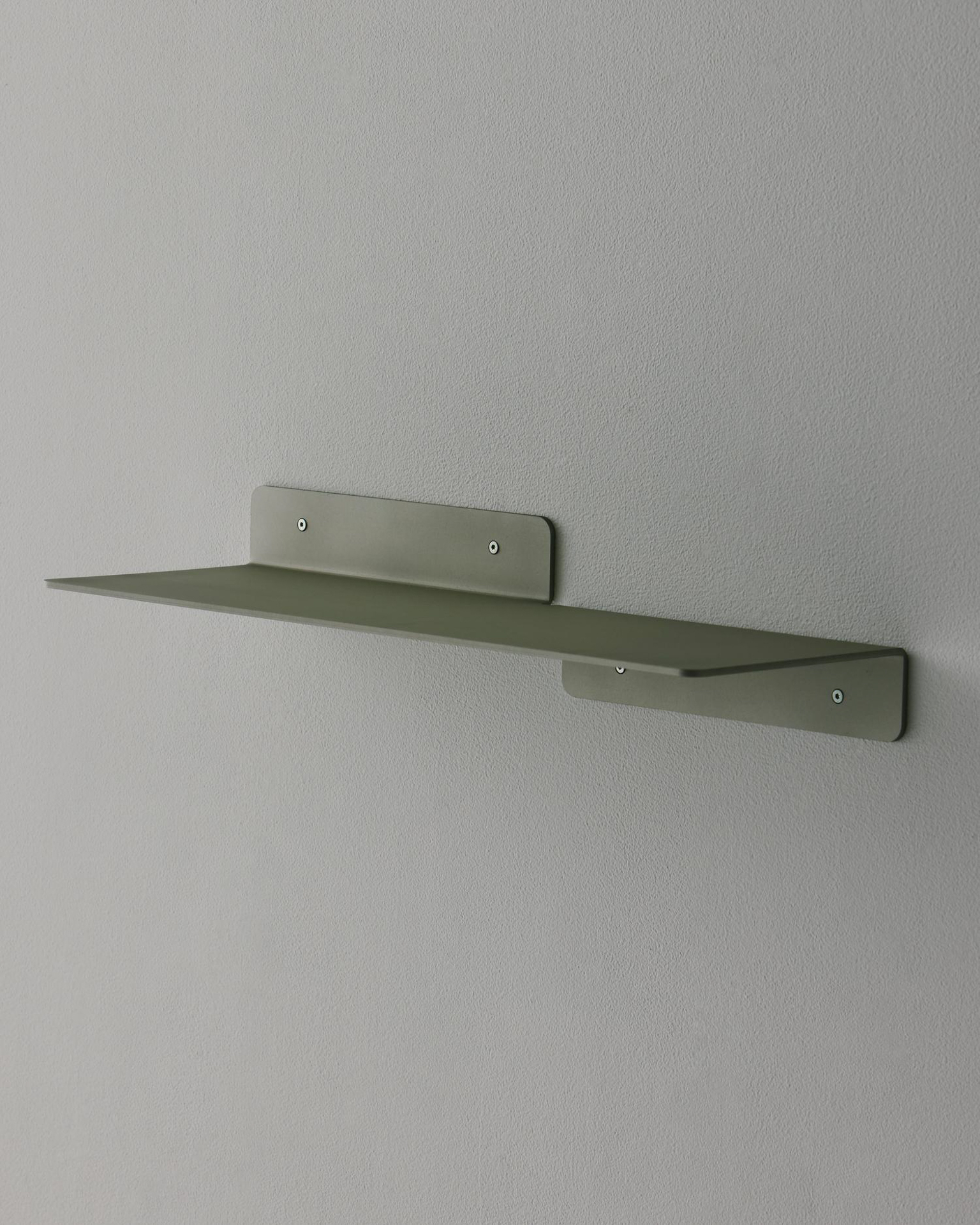 Minimalist sage green metal wall shelf by LESORR against a grey wall