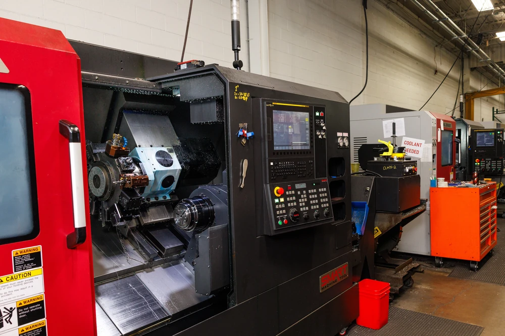 Open CNC lathe showing its turret and chuck, with the rest of the turning cell behind it