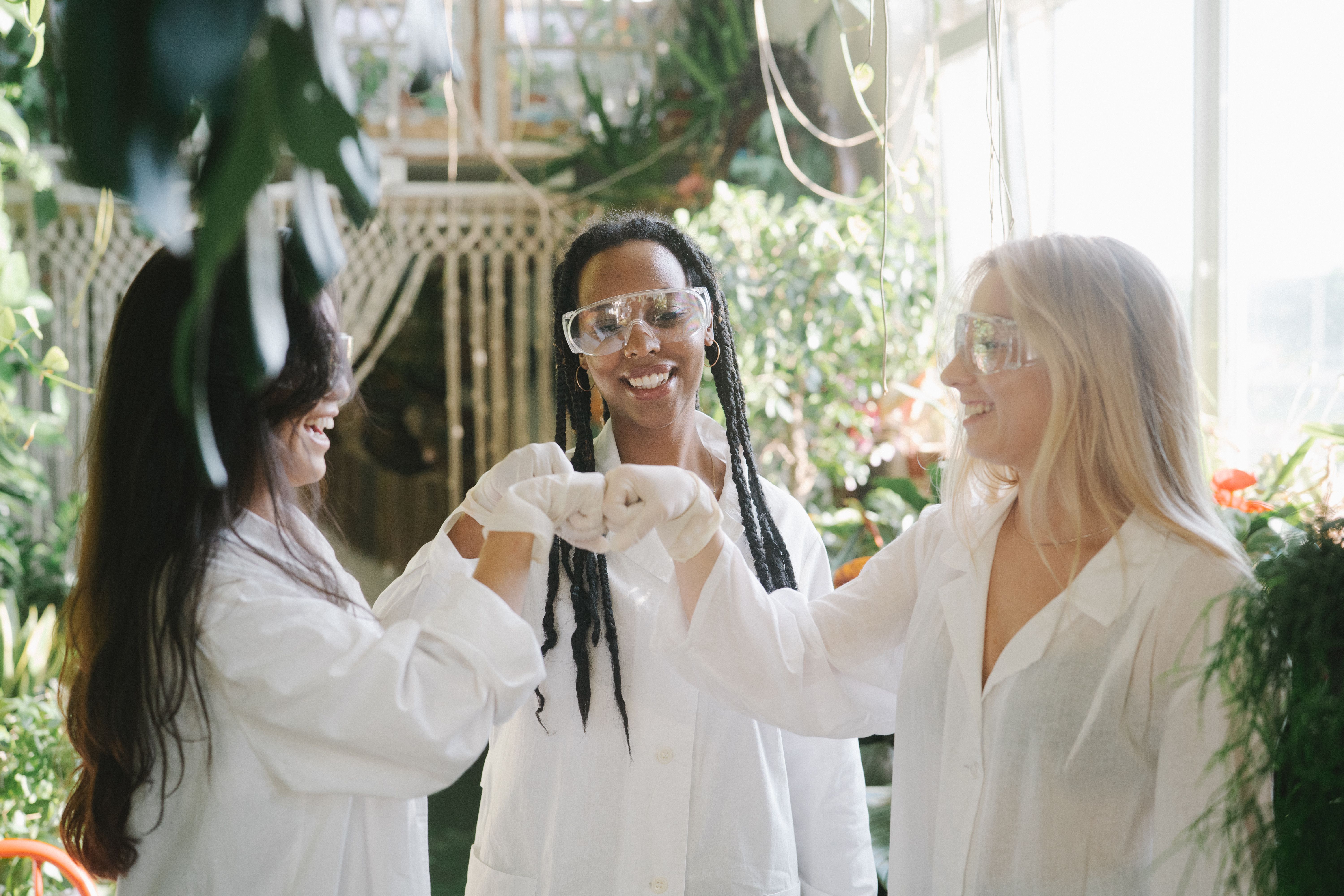 three female scientists fist bumping