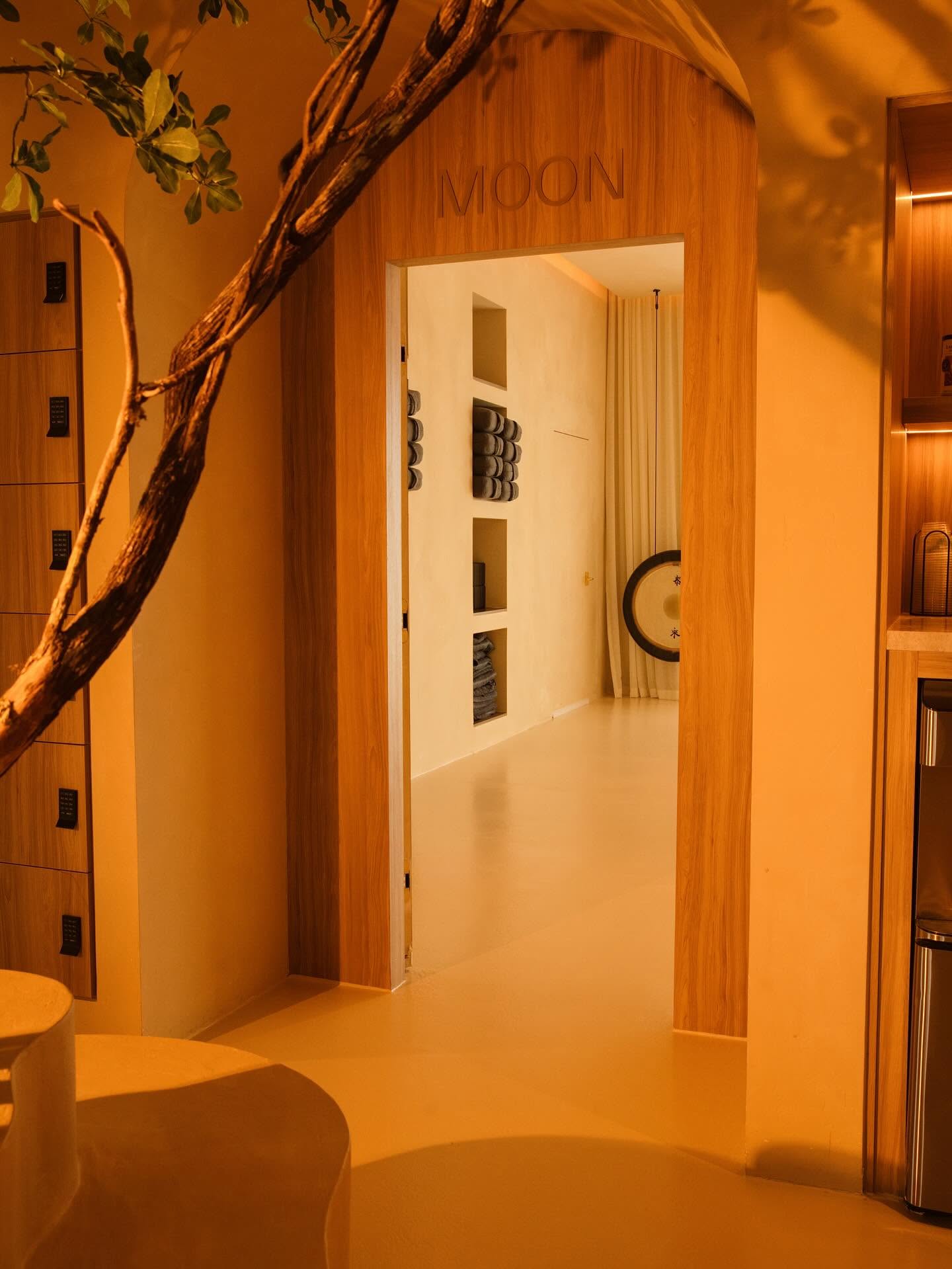 Arched wooden doorway labeled Moon leading into a serene practice room with a gong at Kintsugi Yoga's The Bend studio in Las Vegas