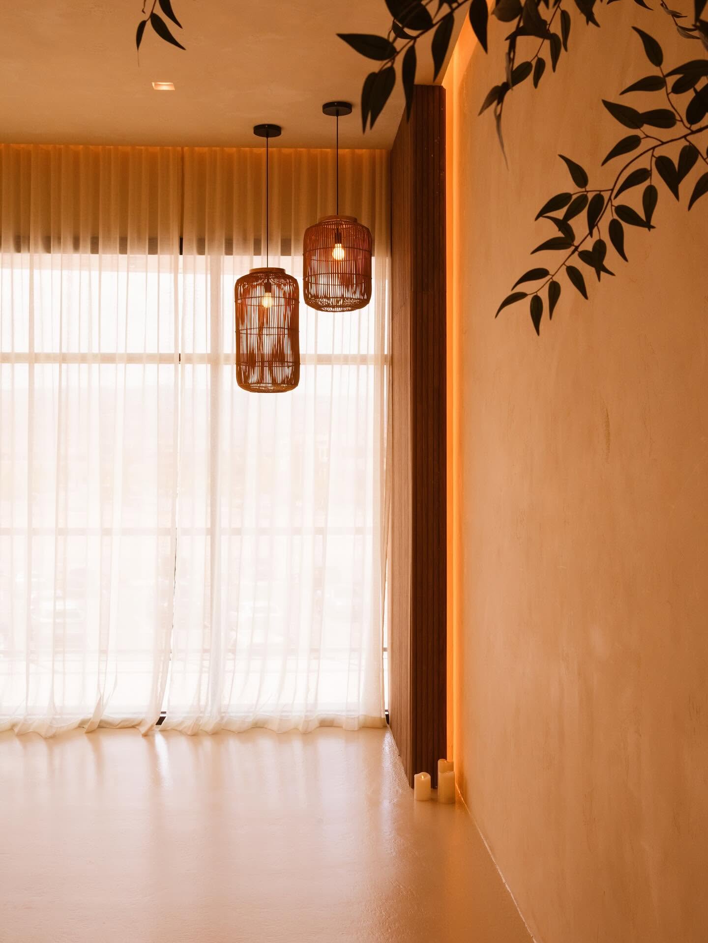 Sunlit room with rattan pendant lamps and sheer curtains at Kintsugi Yoga's The Bend studio in Las Vegas