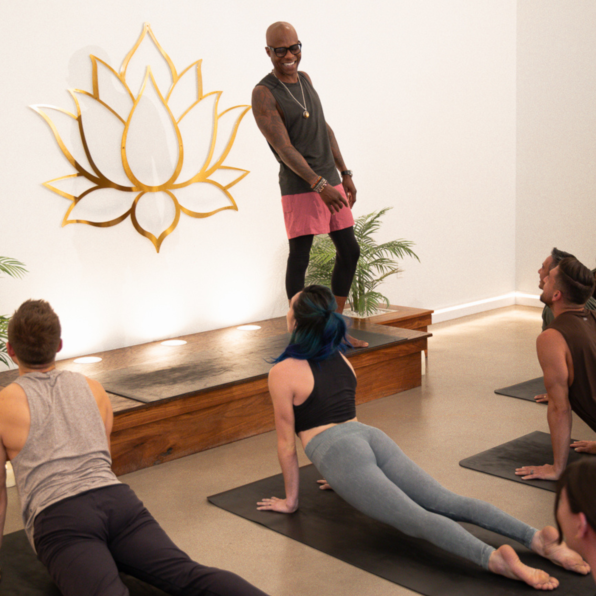 Small group yoga class practicing beneath a golden lotus emblem at Kintsugi Yoga in Las Vegas