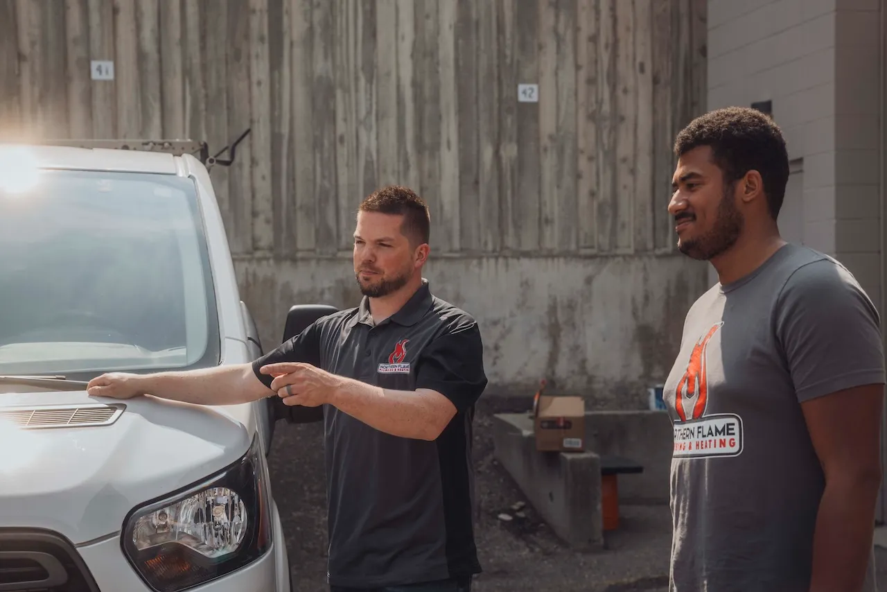 Two Northern Flame team members talking beside a white service van outside the shop
