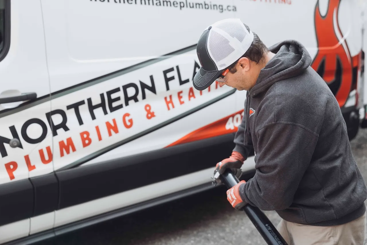 Northern Flame plumber fitting black pipe beside a branded service van