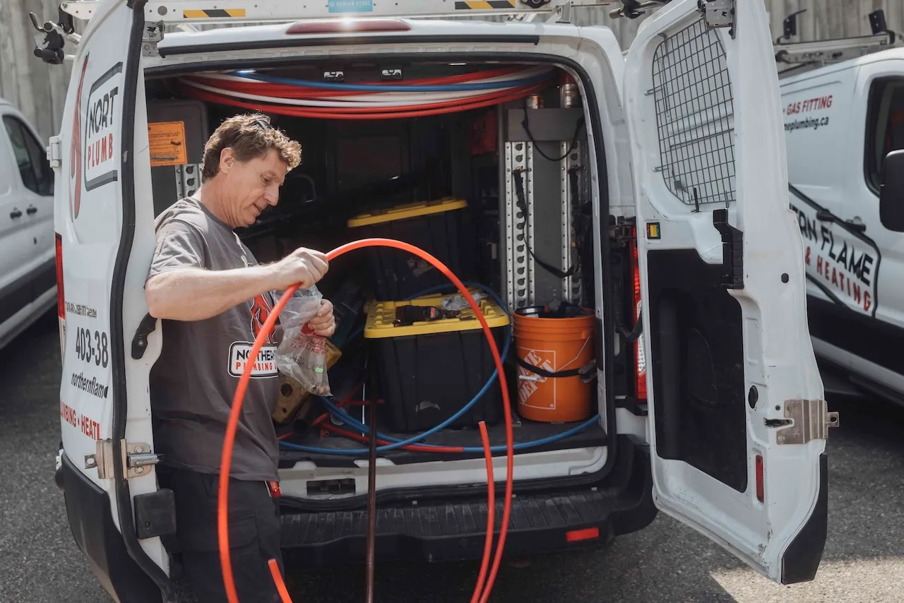 Northern Flame technician pulling drain-cleaning cable from the back of a stocked service van